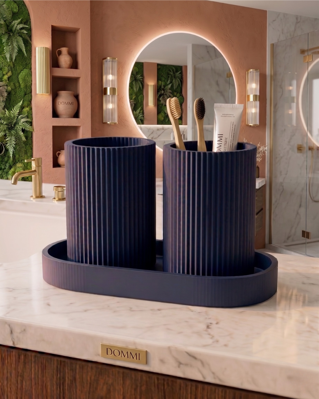 Organizador de bancada minimalista NORD na cor azul navy fosco, com copos canelados contendo escovas de dentes de bambu e pasta de dentes, sobre lavatório de mármore em ambiente sofisticado com detalhes dourados.