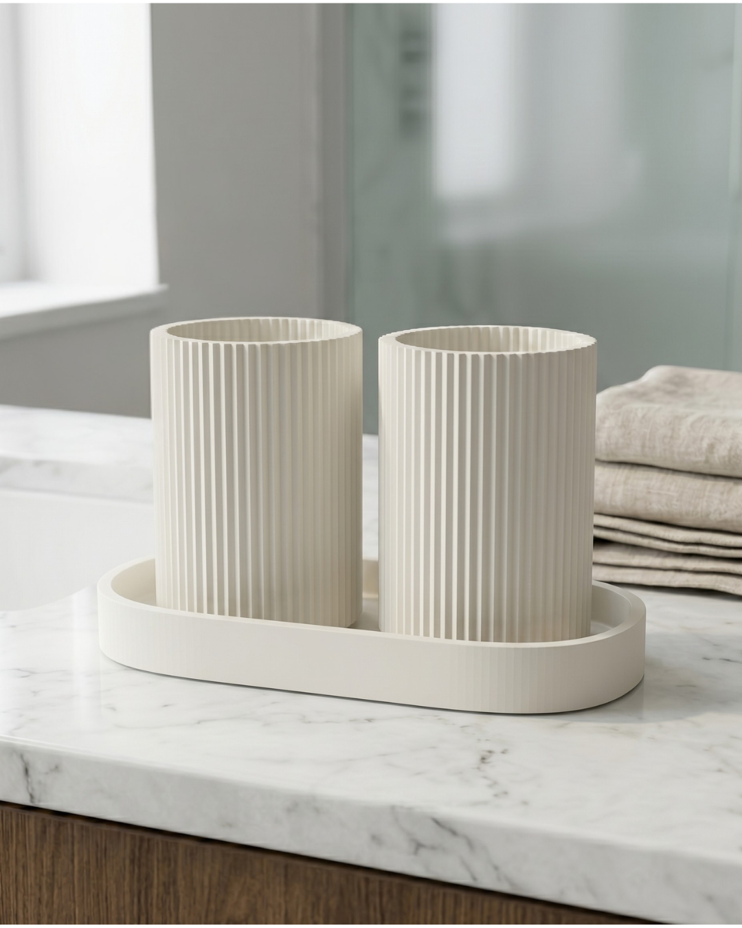 Organizador de bancada NORD na cor Ivory White com acabamento matte, exibindo escovas e pasta de dentes dourada, integrado numa casa de banho premium com espelho redondo e torneira dourada.
